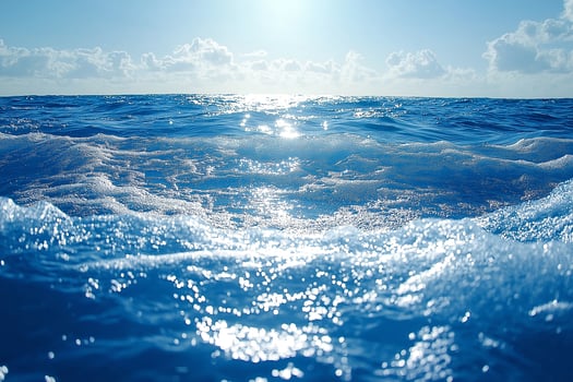 A serene ocean view, with shimmering blue waves and soft white foam reflecting the sunlight, creating a tranquil atmosphere. photo