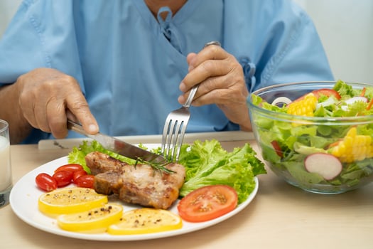 Asian senior woman patient eating pork chop and vegetable photo