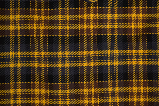 Close-up of a yellow and black plaid fabric texture.Classic checkered textile pattern, warm flannel material for fashion photo
