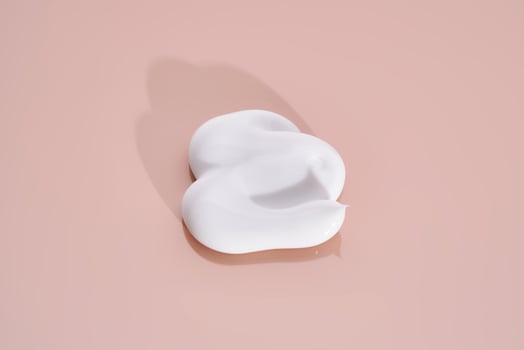 The texture of white cream on a pink background. photo
