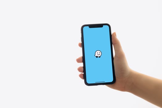 Zaporizhia, Ukraine - January 10, 2025. A woman holds an iPhone with the Waze app logo on the screen while using a mobile app for business at home. white background photo