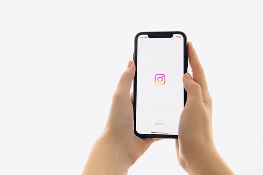 Zaporizhia, Ukraine - January 10, 2025. A woman holds an iPhone with the Instagram app logo on the screen while using a mobile app for business at home. white background photo