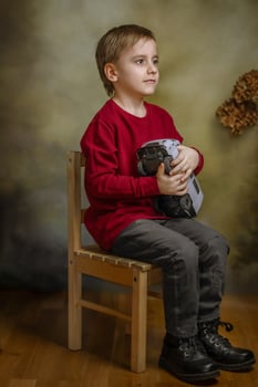 A boy sitting on a chair holding a camera photo