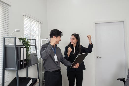 Excited business professionals celebrating success with raised fists in an office environment. photo