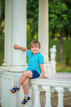 A young boy sitting on a pillar in a park photo