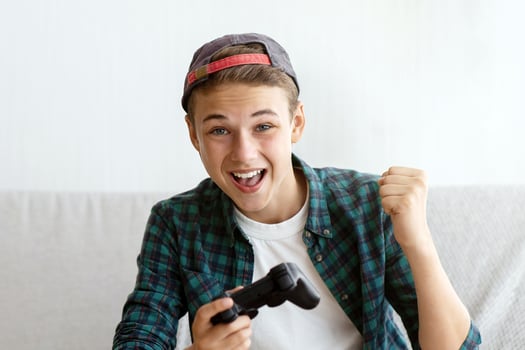 Positive teenager playing games at home, eating junk food, enjoying his free time photo