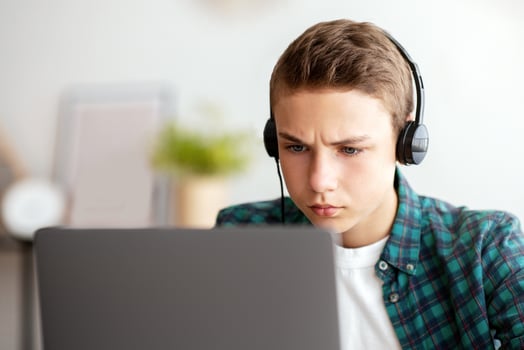 Closeup photo of serious school boy studying online from home, copy space