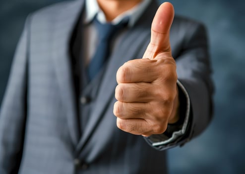 Closeup businessman in suit shows thumbs up sign. Approval positive gesture. A symbol of good job well-done. Business concept. photo