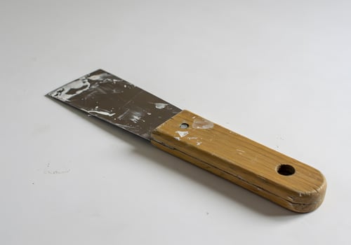 Close-up of a Used Putty Knife with Wooden Handle on White Background photo
