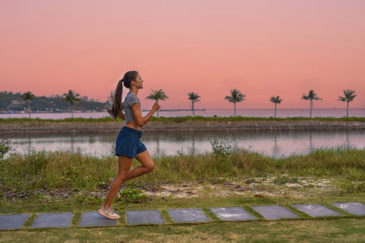 Young slim woman runs doing and sport exercises against sunset and beach with palms photo