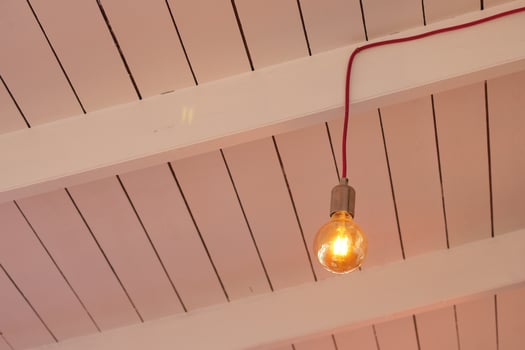 Bright vintage light bulb hanging from white wooden ceiling photo