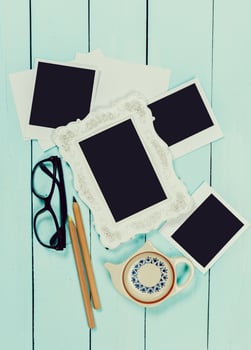 Creative workspace with photographs, stationery, and a teapot on a light blue wooden table photo
