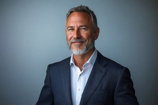 Professional man with gray beard in a tailored suit smiles against a neutral background photo