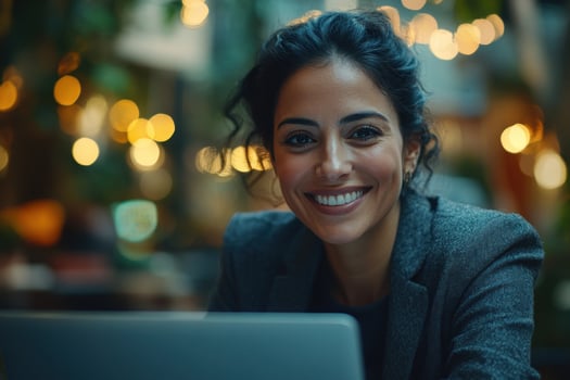 Professional woman smiling while working on laptop in a cozy, warmly lit cafe setting photo