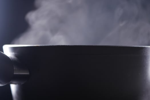 Steam rising from a black pot during cooking preparation photo