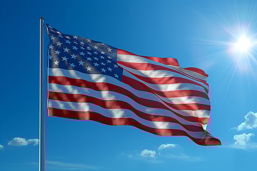 Waving stars and stripes in a bright blue sky with fluffy white clouds overhead. photo