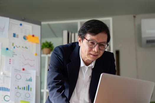 Senior financial consultant engaging with budget data and laptop in a contemporary workspace. photo