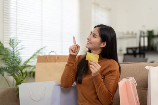 Joyful woman celebrating her online shopping experience, holding a credit card and pointing with excitement. photo