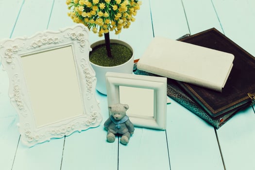 Home decor arrangement with empty frames, a teddy bear, and a small plant on a wooden surface photo