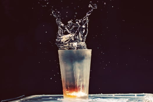 A glass of water with ice and water splashing photo