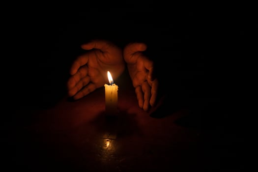 A candle is lit in the dark with two hands photo