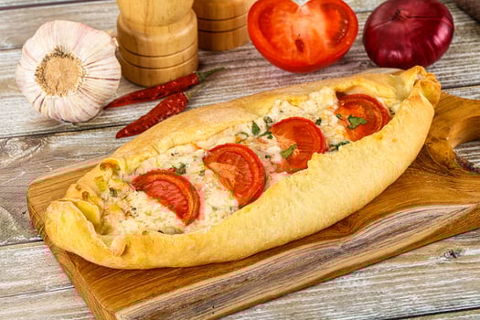 A bread roll with tomatoes and garlic on a cutting board photo