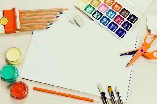 Art supplies arranged on a table with blank paper, colored pencils, watercolors, and brushes for creative projects photo