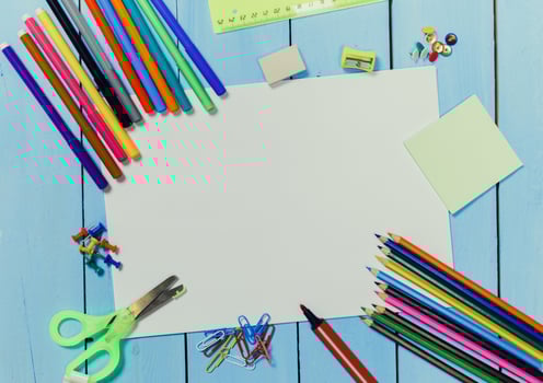 Creative workspace with colorful art supplies arranged around blank paper on a blue wooden table photo