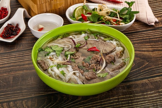 A bowl of soup with meat and vegetables on a table photo