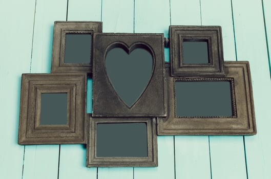 Photo frame with heart shape design displayed against a light blue wooden backdrop