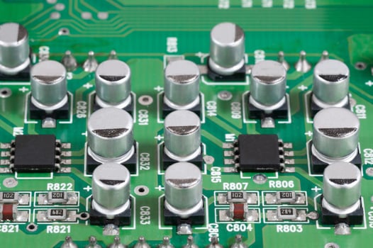 Close-up view of green electronic circuit board showing aluminum capacitors and integrated components with intricate connections photo