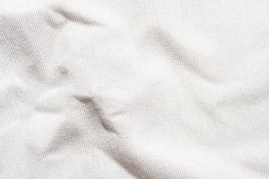 Close-up texture of white wrinkled canvas fabric with subtle shadows. photo