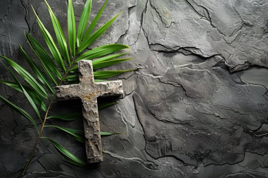 Palm Sunday. Stone cross with palm leaf on gray stone background with copy space. Religion, faith, Christianity concept photo