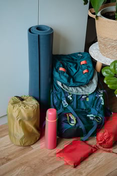 A vibrant blue backpack can be found resting on a smooth wooden floor, positioned right beside a neatly rolled yoga mat, suggesting a blend of travel and wellness activities photo