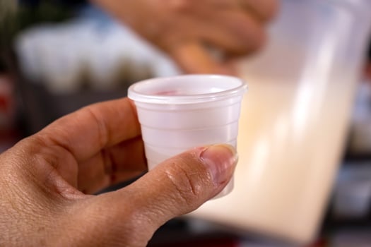 Plastic cup with the traditional pulque drink. Tourist guide showing the importance of the agave at the Teotihuacan archaeological site. photo