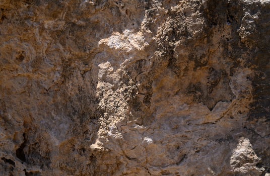 Intricate textures reveal the beauty of weathered stone in a sunlit landscape photo