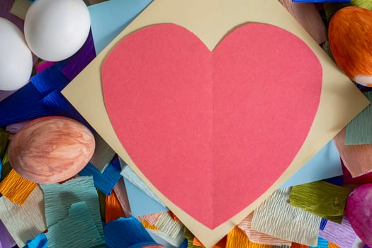 A heart shaped paper is surrounded by colorful eggs photo