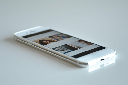 A sleek smartphone displaying a gallery of images on a white surface. photo