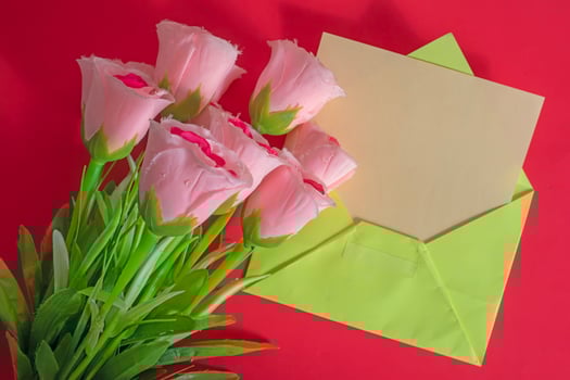 Pink tulips and envelope on red background photo