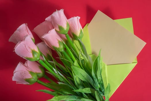 A bouquet of pink flowers and a note on a red background photo