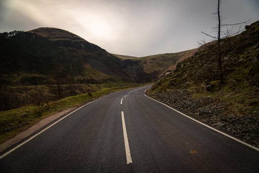 Winding mountain road disappearing into the valley below photo