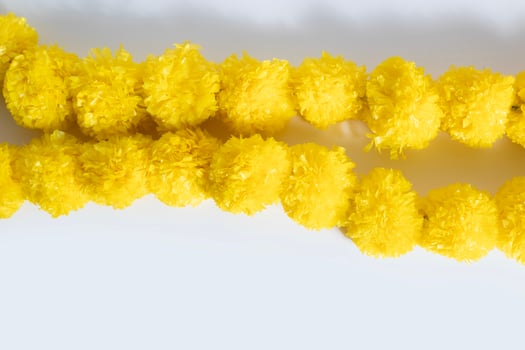 Beautifully decorated bright yellow artificial flower garland on a white background. photo