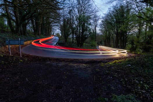 Long exposure of cars on winding forest road photo