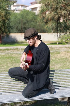 Male Street Artist Enjoys Playing Classical Guitar In A City Park photo