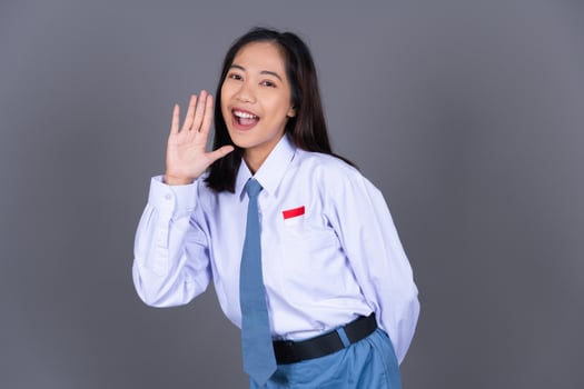 Indonesian Girl High School Student in Uniform Shouting with Hand on Mouth Isolated Background photo