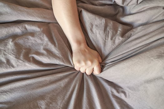Close up of a person hand gripping grey wrinkled fabric with strength and emotion. photo