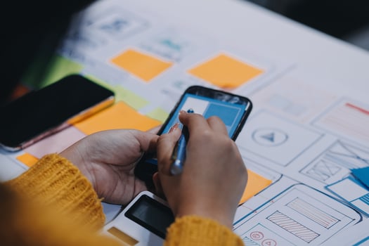 A woman using her smartphone to design a website photo