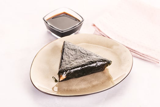 A piece of sushi on a plate with a glass of sauce photo