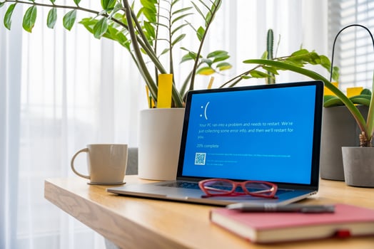 Prague, Czech Republic - September 13, 2024. Sad laptop with blue screen error near the window photo