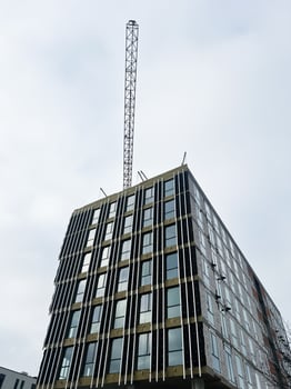 Modern high-rise building under construction with metallic framework against cloudy sky photo